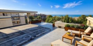 Appartamento vista mare con piscina sul rooftop e lettini per relax tra oceano e design.