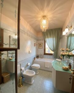 Bagno elegante Villa Montecalvoli: vasca, wc e specchi antichi.