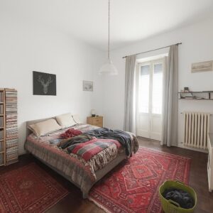 Camera da letto bianca con letto a due piazze, librerie rosonye e coda di cervo.