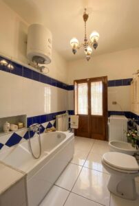 Bagno elegante in casale a Camaiore: vasca, due toilet e lampadario, rustico Versilia vista mare.