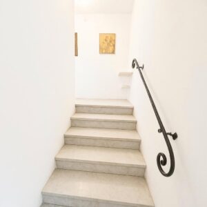 Scala moderna in pietra leggera, handrail nero, luce naturale e arte textured.