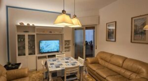 Soggiorno e sala da pranzo accoglienti in appartamento vista mare con divano in pelle e balcone.