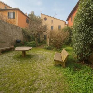 Giardino interno di villa nel centro storico di Pisa con prato, panchine in pietra e barbecue