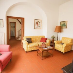 Sala da vivere rustica con arco terracotta e toni accoglienti.