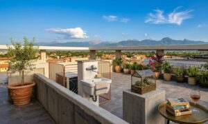 Terrazza appartamento vista mare con vino, libri e montagne per un relax tra le piante.