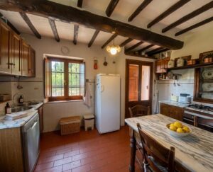Cucina rustica in casale a Camaiore: cotto, travi e isola in marmo con limoni.