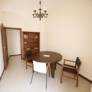 Ambiente minimalista luminoso con tavolo in legno scuro e libreria elegante.