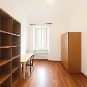 Villa con giardino centro storico Pisa: stanza luminosa con tavolo, sedia, scaffale e armadio.