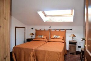 Letto rustico illuminato da luci naturali con pavimento terracotta.