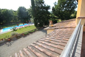 Vista dal balcone del resort: piscina, prato verde, sedie e cielo sereno.