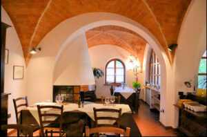 Soffitto a barrel-volt in mattoni rossi, tavola da pranzo e finestra arcosella.