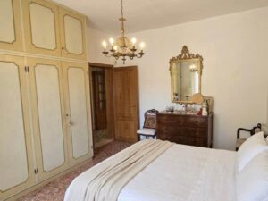 Un letto grande in camera da letto elegante con armadio a muro e specchio dorato.
