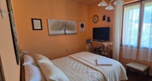 Camera accogliente con muri terracotta, letto bianco e luci soffusa.