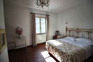 Camera da letto accogliente con piumone floreale, testiera in legno e vaso di fiori.