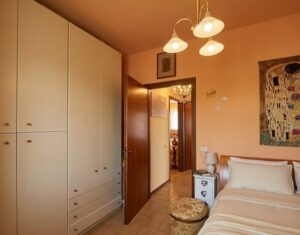 Camera da letto accogliente con armadio bianco e pendola gold.