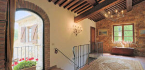 Prestigioso casale: scala in mattoni rossi con porta ad arco e vista sul patio fiorito.