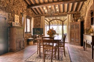 Accogliente sala da pranzo in prestigioso casale con mattoni, legno e luce naturale.