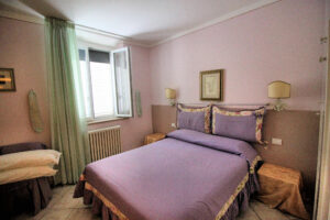 Camera rosa con letto lilla in villa storica dominante, panoramica con parco e piscina.