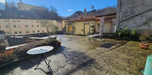Cortile sereno con giardino pensile sulle mura a Castelnuovo di Garfagnana, vista sul castello.