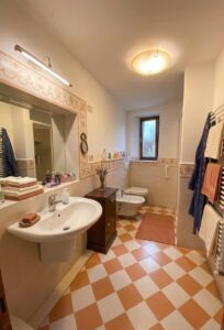 Bagno con pavimento a scacchi arancio e bianco in appartamento ristrutturato a Castelnuovo di Garfagnana.