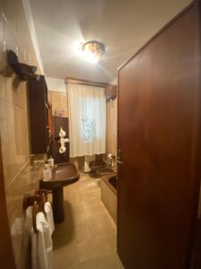 Bagno marrone intimo con vasca curva, lavabo in legno e asciugamani bianchi, luce calda rilassante.