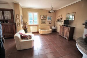 Soggiorno accogliente con divani bianchi, luce naturale e console in legno con TV.