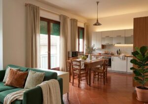 Soggiorno accogliente con divano verde e cucina bianca in appartamento 4 vani Montecalvoli Alto.