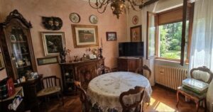 Accogliente sala da pranzo pesca con tavolo rotondo fiorato, sedie in legno e finestra luminosa.