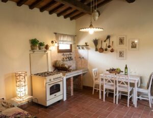 Cucina rustica accogliente nella Tenuta con fonte romana, con tavolo apparecchiato e travi a vista.