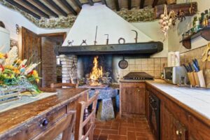 Accogliente cucina rustica con camino acceso e isola in legno, in prestigioso casale.
