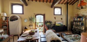 Soggiorno rustico e luminoso con travi a vista, tavolo in legno e porta finestra sul verde