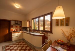 Cucina crema con isola e sala da pranzo, vista mura, appartamento ristrutturato Castelnuovo di Garfagnana.