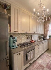Un cucina elegante con armadietti paneleggiati, marmo grigio e chandelier ornato.
