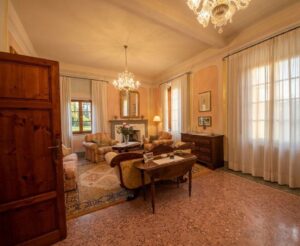 Soggiorno rosa con camino, terrazzo rosato e poltrone in luce naturale.