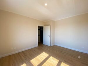 Stanza vuota minimalista con lucernari a terra e parquet chiaro, luminosa e sobria, senza arredi.