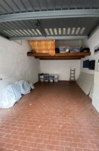 Un vasto garage funzionale con mattoni rossi, soffitto in metallo e scaffale robusto.