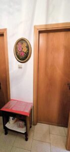 Ingresso domestico con porte in legno, quadro floreale e tavolino.