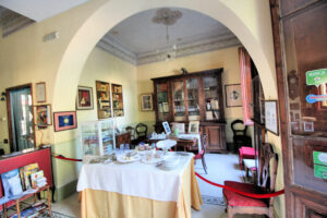 Sala da pranzo d’epoca con tavola apparecchiata, arredi antichi e vetrina museale
