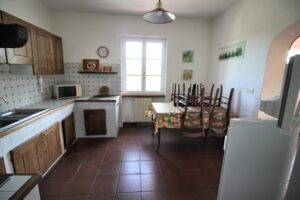 Luminosa cucina con armadi in legno e sala da pranzo floreale con finestra.