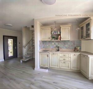 Cucina moderna crema con scale grigie, luce naturale ed mensole decorative in ambiente luminoso.