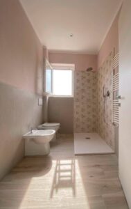 Bagno rosa moderno e minimale con doccia, finestra e luce naturale: elegante e accogliente.