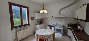 Cucina rustica con tavolo da pranzo, finestra luminosa e mobili vintage.