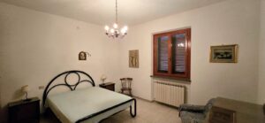 Camera da letto tradizionale con letto matrimoniale in ferro e arredi in legno.