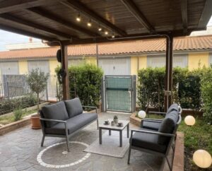 Pergola scura, luci accoglienti e sofà moderno su patio elegante.