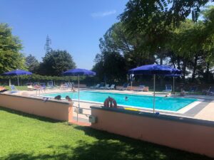 ALT: Piscina ornata con umbrella trabtímino in un giardino elegante.