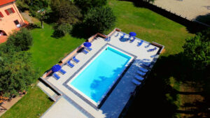 Piscina turquesa, lettini blu e verde foltissimo in giardino.