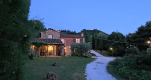 Prestigioso casale in pietra con viale curvo e giardino sereno al tramonto.
