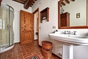 Bagno rustico in prestigioso casale con pavimento a spina di pesce e lavabo su pedistallo.