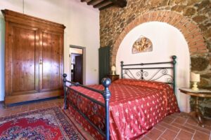 Accogliente camera rustica al prestigioso casale con letto nero e copriletto rosso.