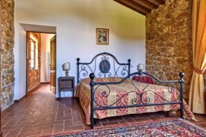 Accogliente camera in prestigioso casale rustico con mattoni e letto in ferro battuto.